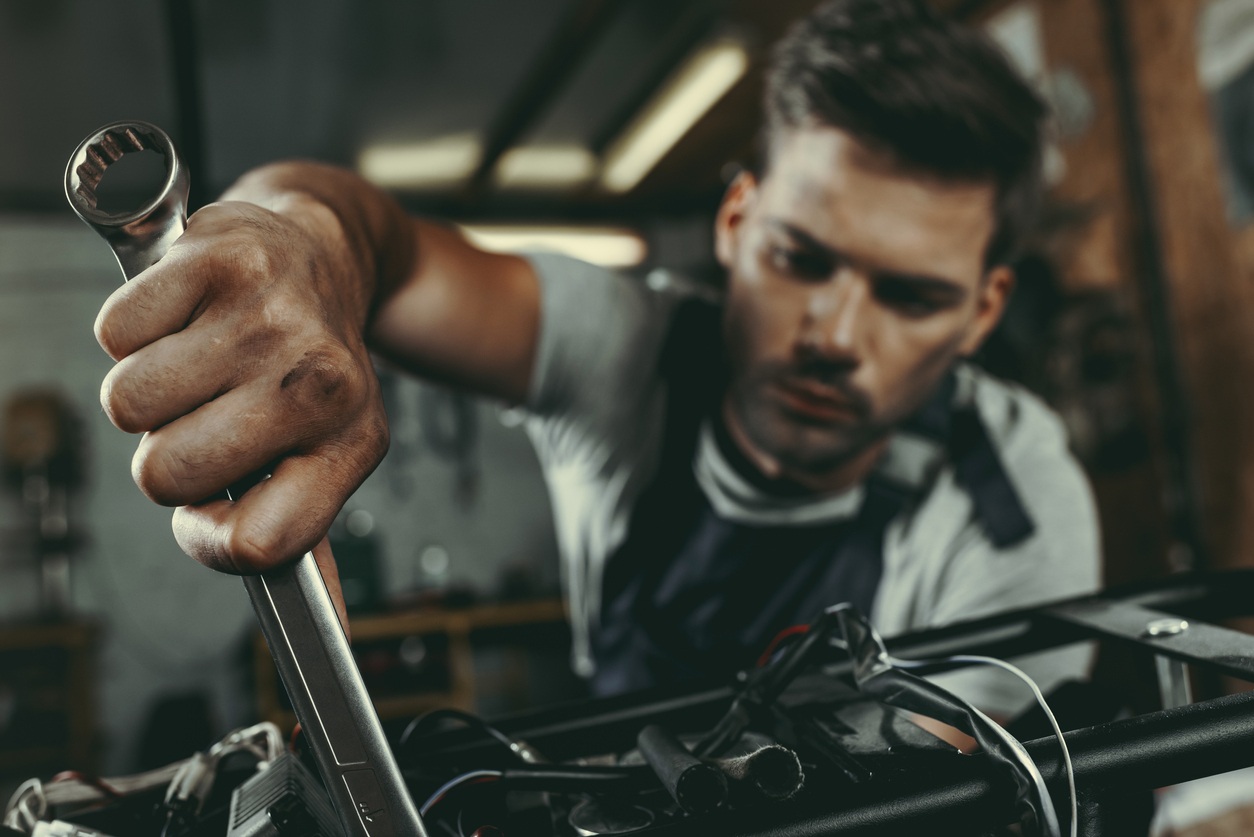 young handsome mechanic repairing motorbike in workshop